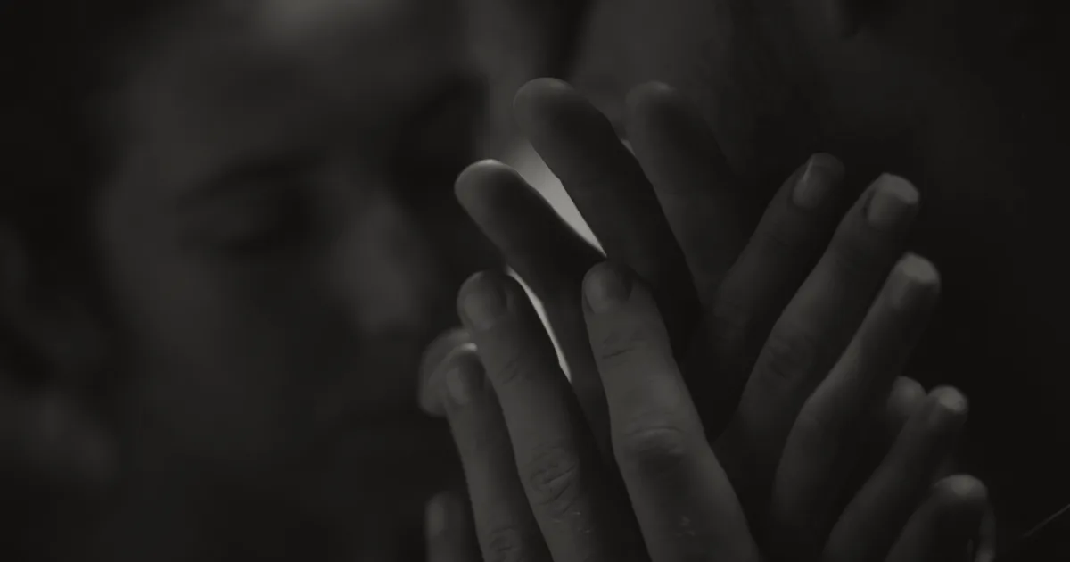 Hands in prayer position, blurred face behind, meditative