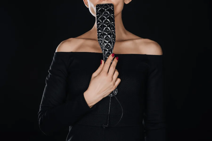 Editorial portrait of Viktoria Sway in glamour styling holding a paddle — impact-play detail.