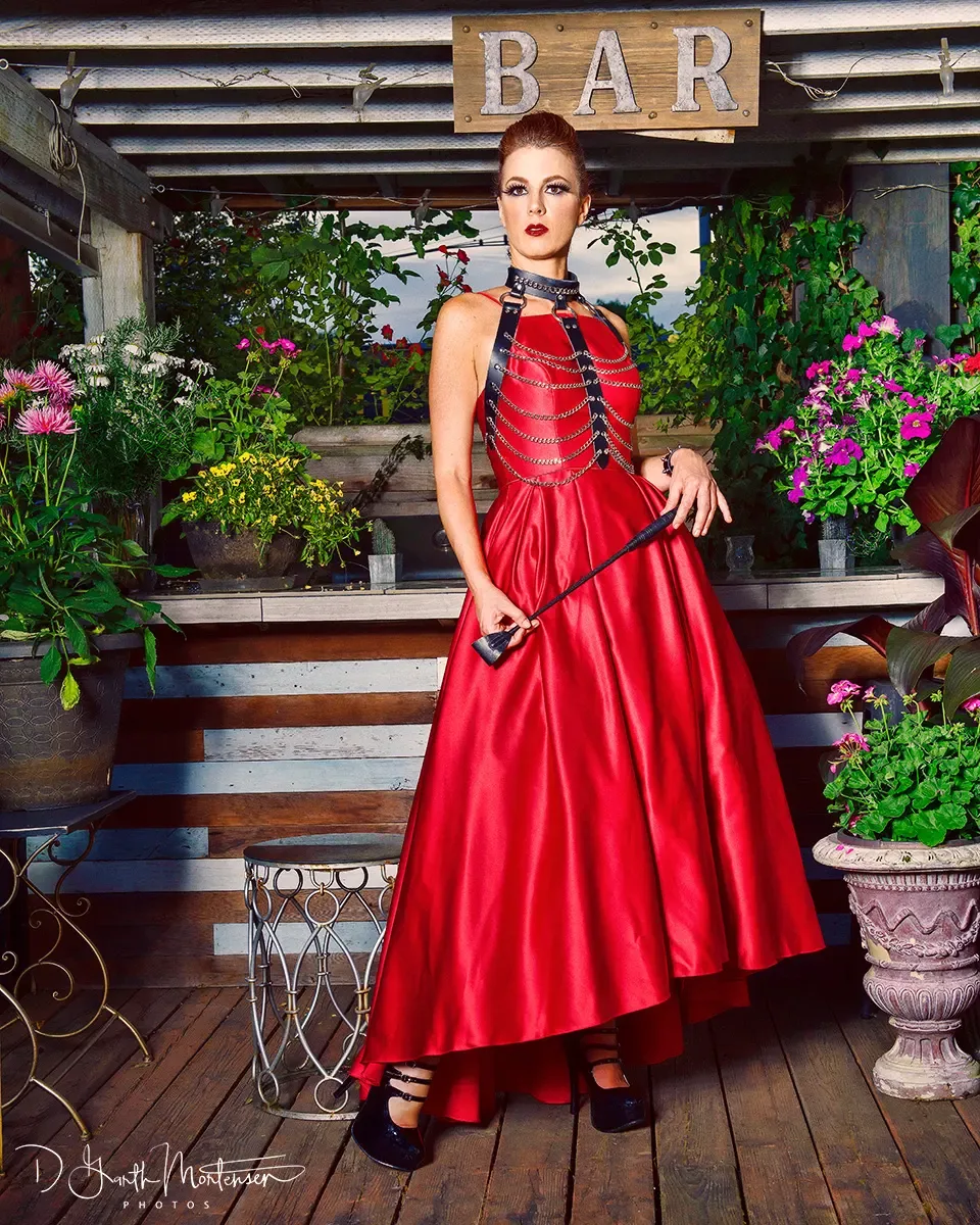 Riding crop in Dominatrix Viktoria Sway's hand, red satin gown, NYC